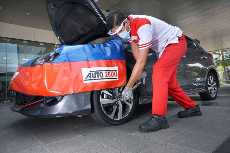 Seorang mekanik Auto2000 memeriksa kondisi ban mobil pelanggan