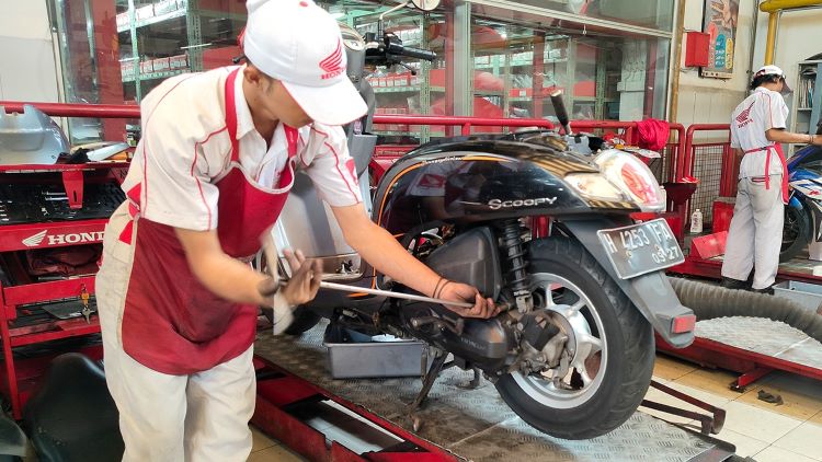 Seorang mekanik AHASS melakukan pemeriksaan dan servis motor kostumer 