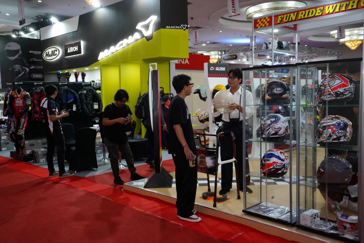 Para exhibitor berinteraksi dengan pengunjung pameran helm dan apparel di pameran IMHAX 