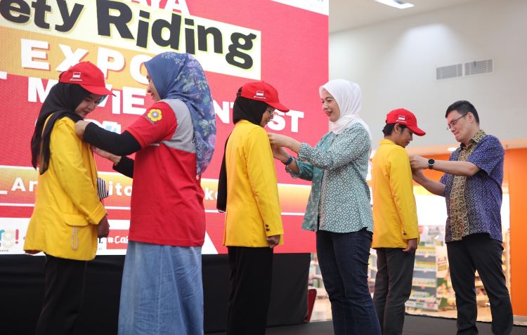 Petinggi Astra Honda Motor memasang pin penghargaan untuk pemenang kontes film pendek kampanye keselamatan berkendara