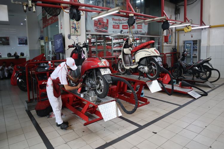 Makanik bengkel AHASS sementara melakukan servis dan perawatan kemotor konsumen