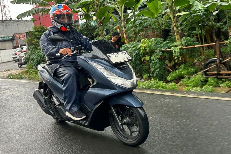 Pemotor berkendara dengan safety saat hujan 