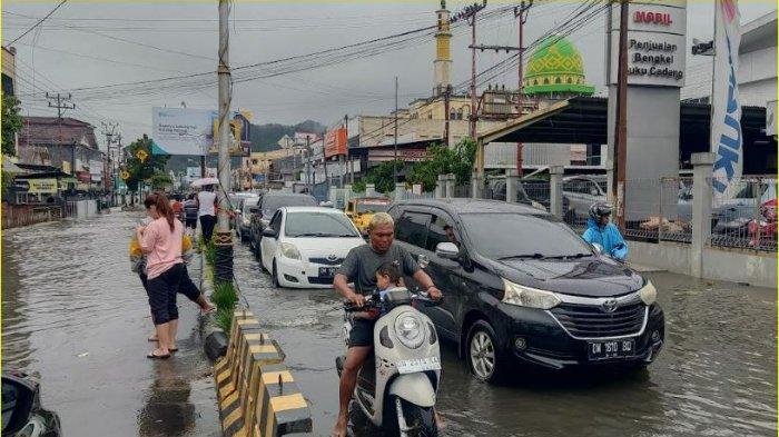 Deretan mobil melintasi jalan yang digenangi bajir karena hujan