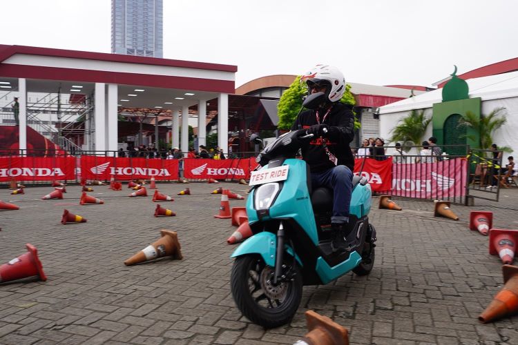 Seorang pengunjung coba menjajal motor listrik Honda di area test ride IIMS 2025