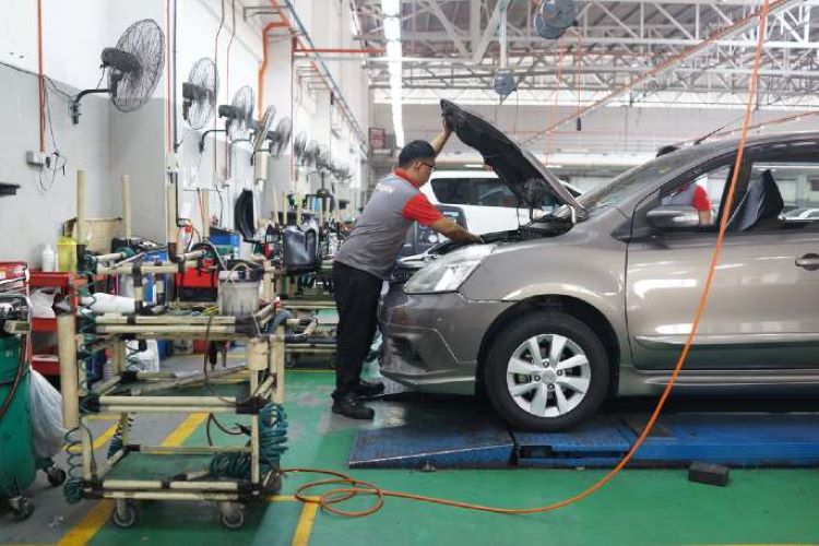 Seorang teknisi Nissan seemntara melakukan pengecekan dan servis mobil konsumen