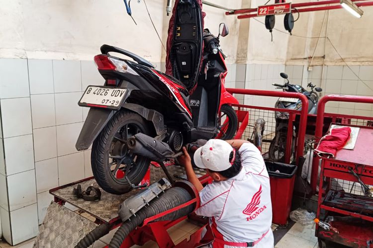 Mekanik Honda sementara melakukan perawatan motor konsumen