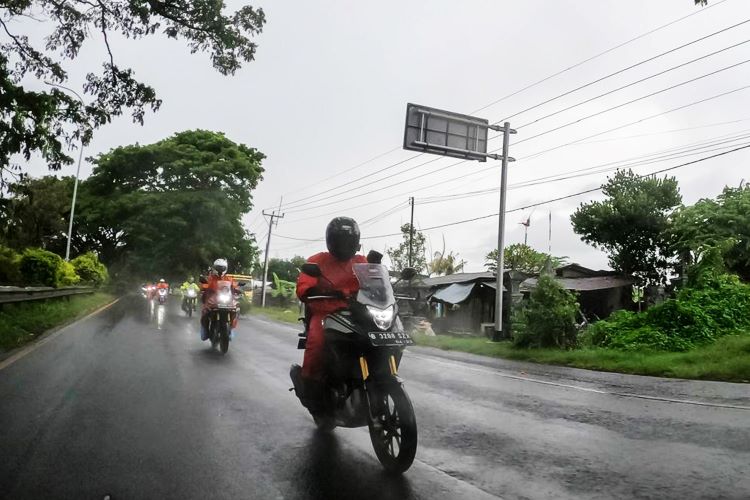 Pemotor menggunakan riding gear lengkap saat berkendara dalam kondisi hujan