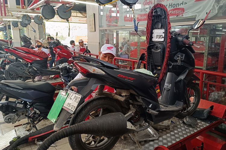 Mekanik Bengkel AHASS sementara melakukan perawatan motor konsumen 