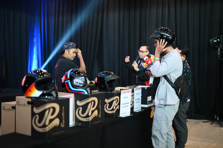 Searing pengunjung mendapatkan helm dengan promo di pameran IMOS 