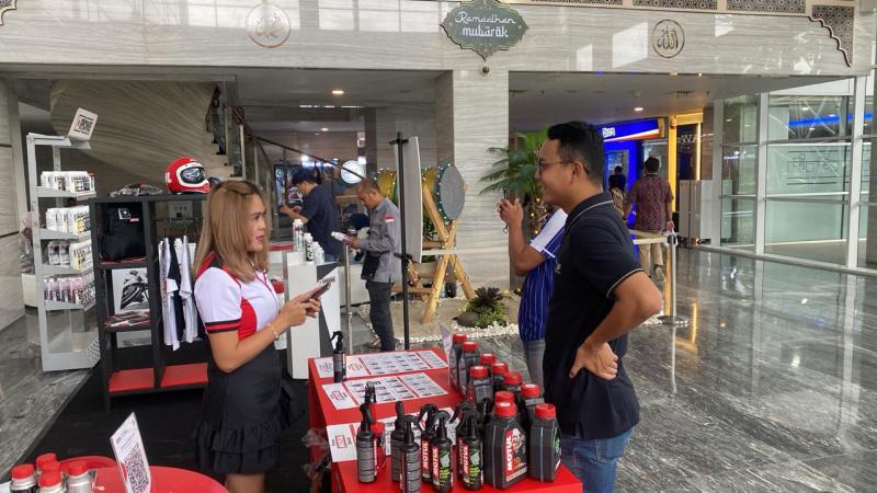 Pramuniaga Motul menawarkan produk pelumas Motul dan iPhone yang menjadi perhatian konsumen 